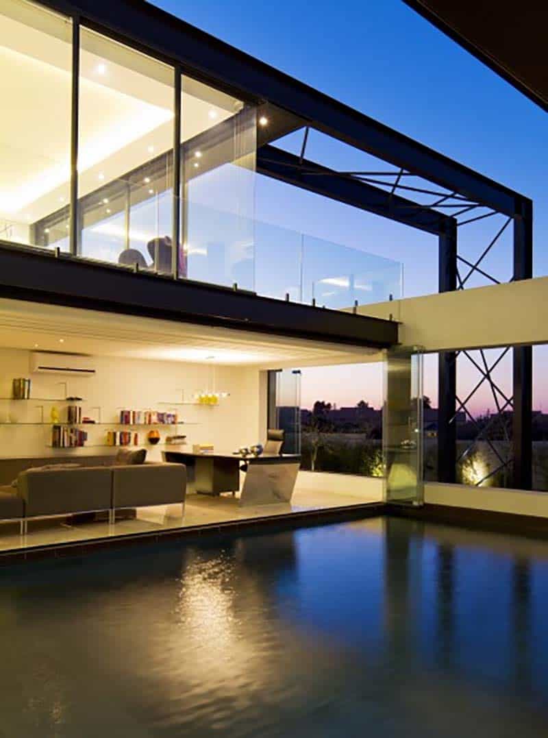 contemporary glass house with a pool at dusk