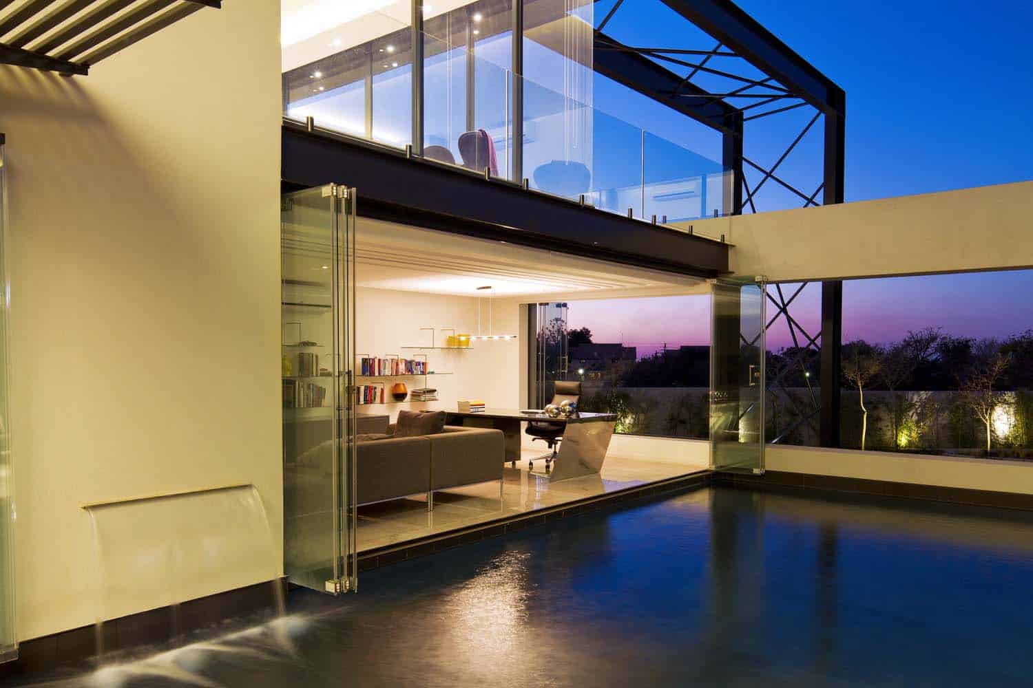 contemporary glass house with a pool at dusk