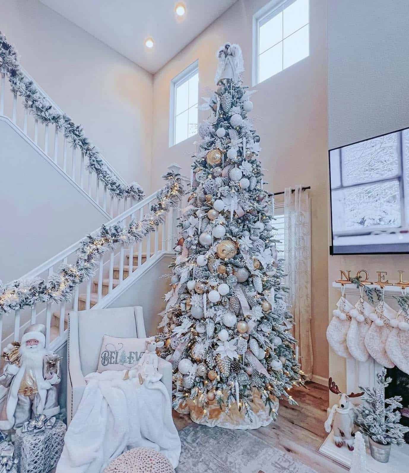 christmas-decorated-living-room-with-a-flocked-tree-and-garland-on-the-staircase