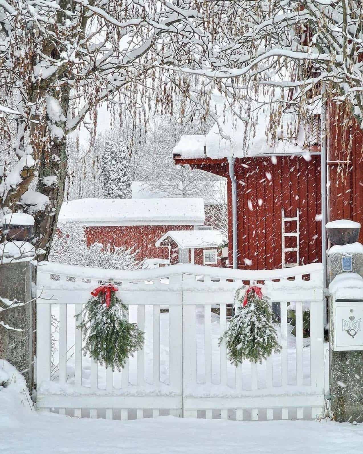 a-winter-wonderland-scene-with-a-red-house-white-fence-and-wreaths