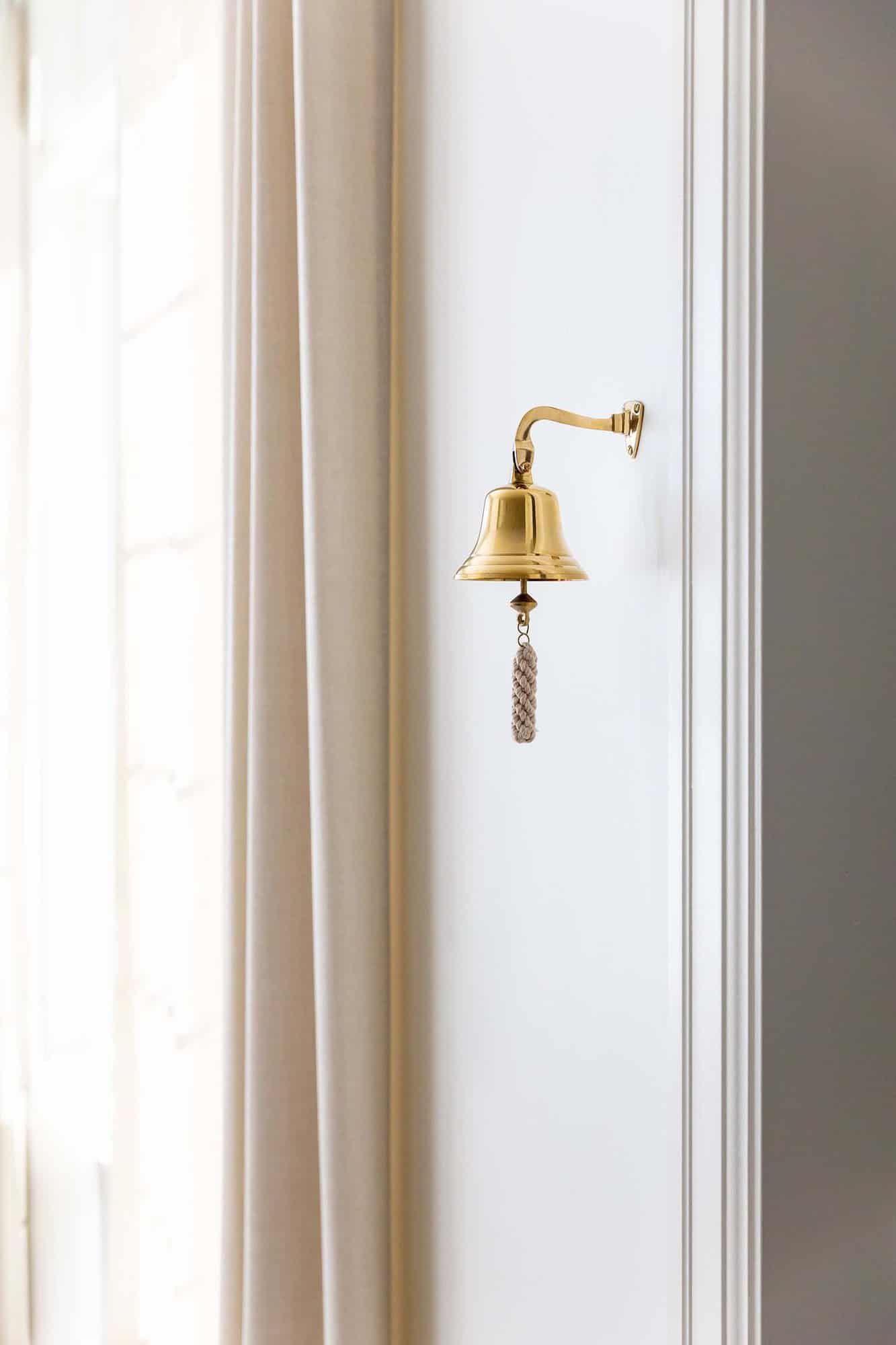 traditional-style-wall-detail-brass-dinner-bell-leading-into-pantry