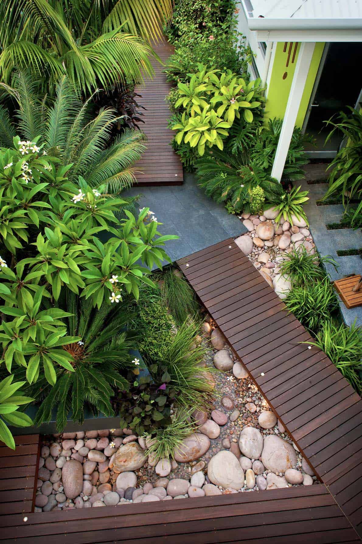 subtropical-contemporary-courtyard-with-wood-pathway-over-river-rocks