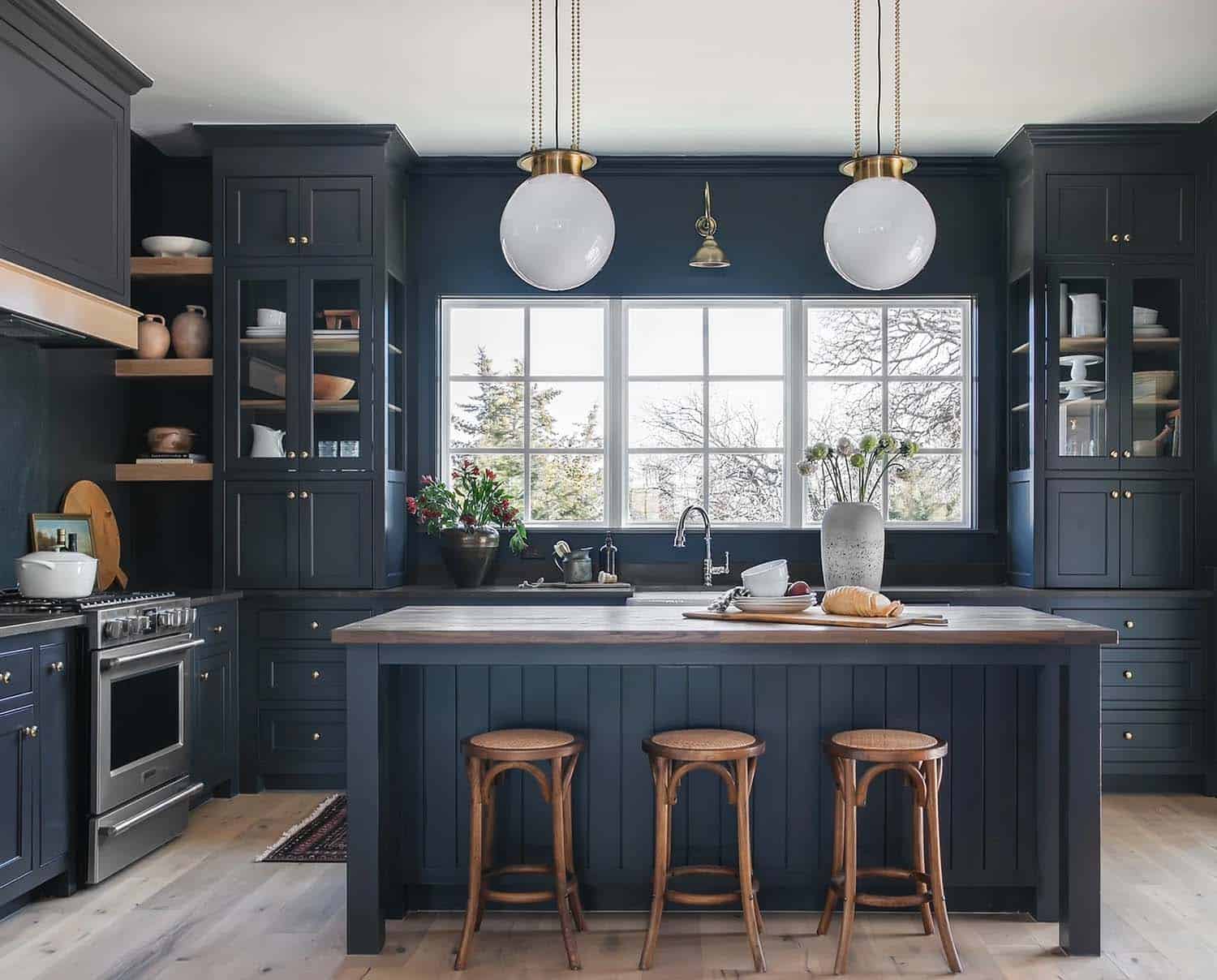 transitional-style-kitchen-with-dark-blue-cabinets-and-ball-pendants