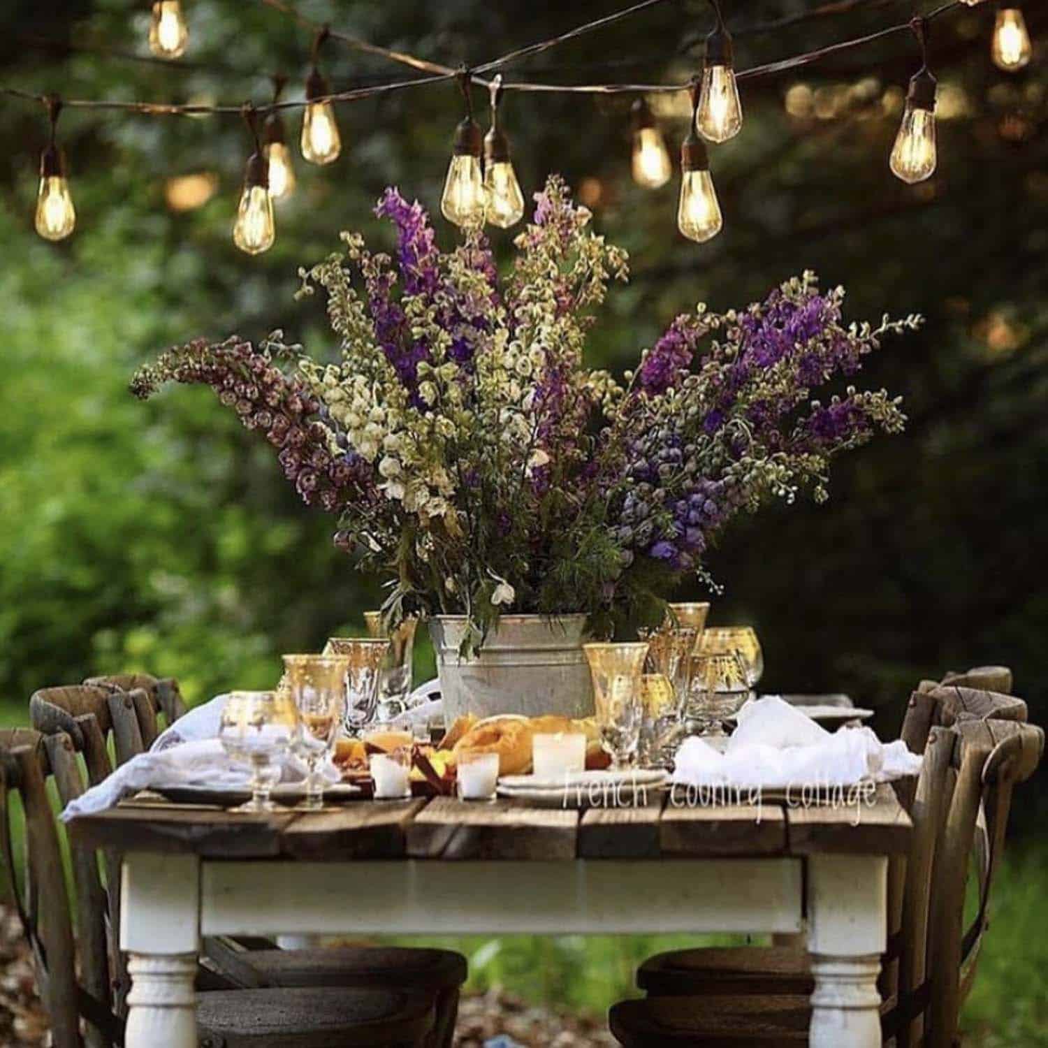 outdoor dining table with gardens and string lights