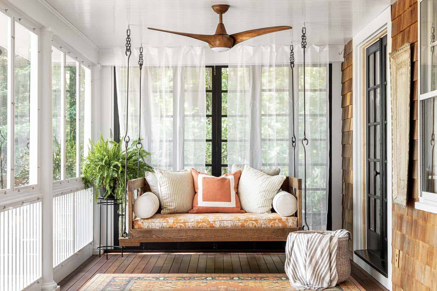 coastal screened-in porch with a swing and ceiling fan