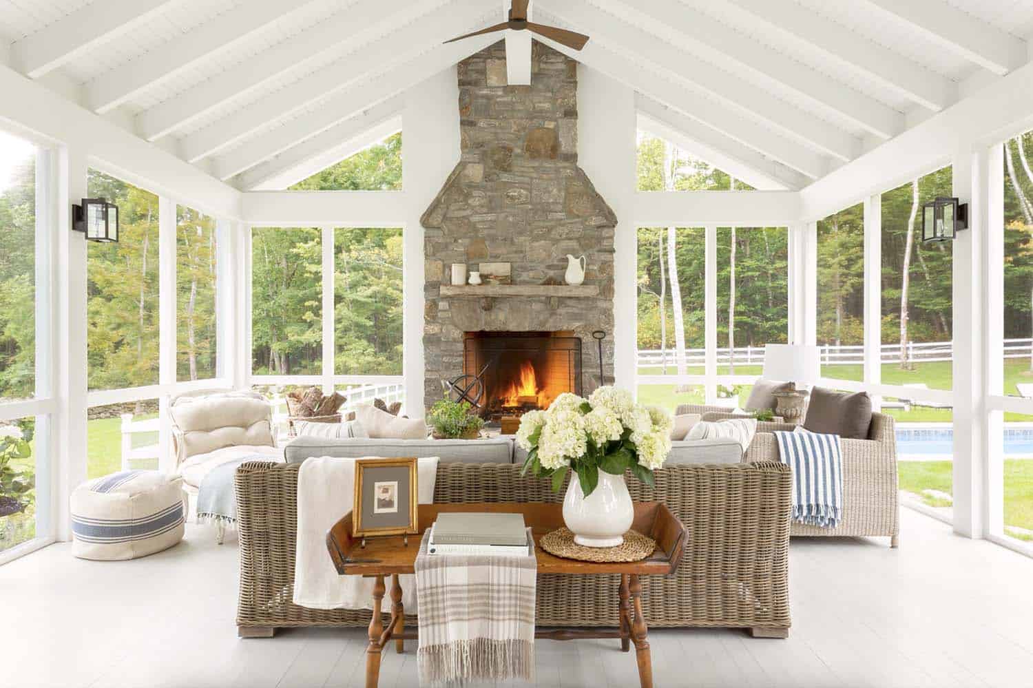 cozy farmhouse screened porch with a stone fireplace focal point