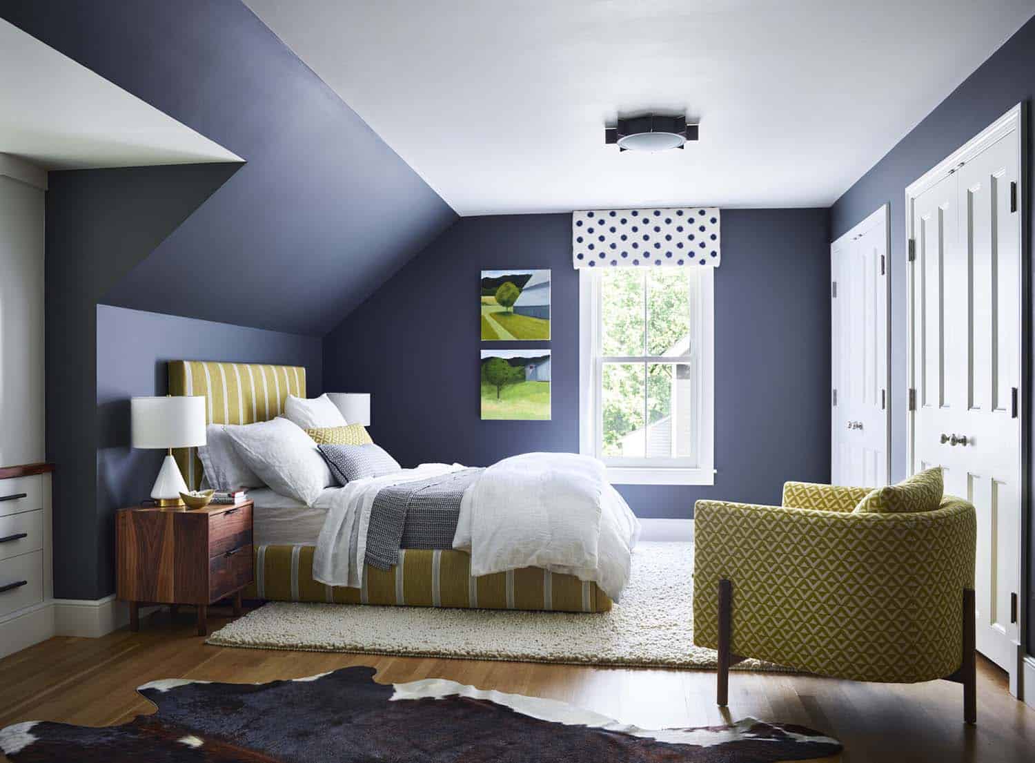 contemporary bedroom with dark blue walls and an angled ceiling