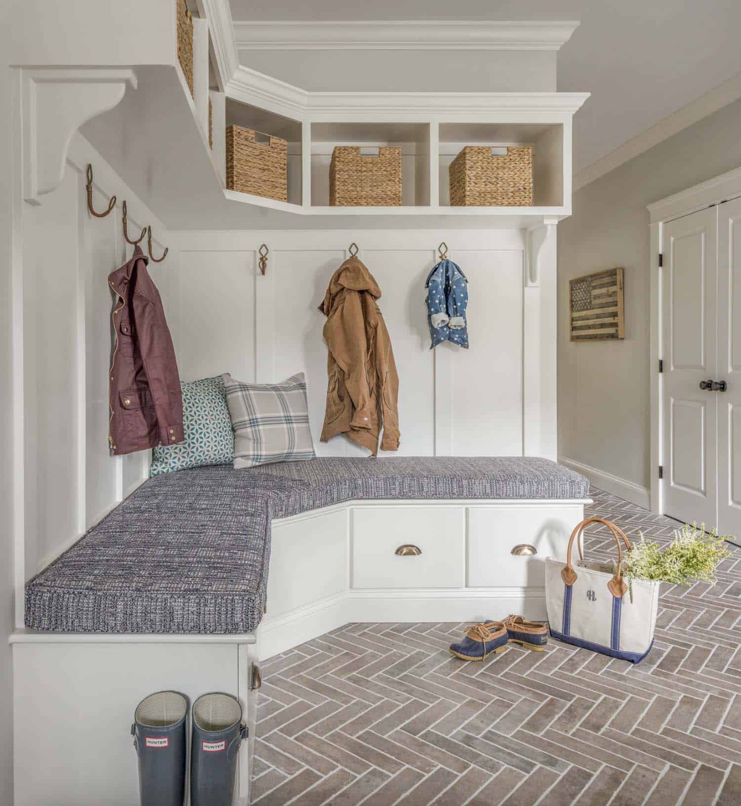farmhouse mudroom with a bench and brick herringbone flooring