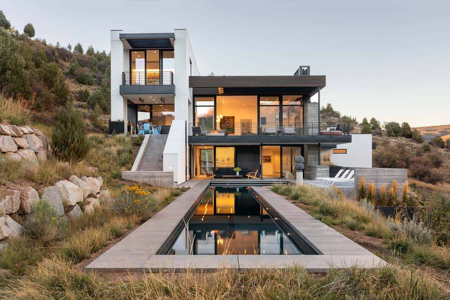 mountain modern home exterior with a lap pool at dusk