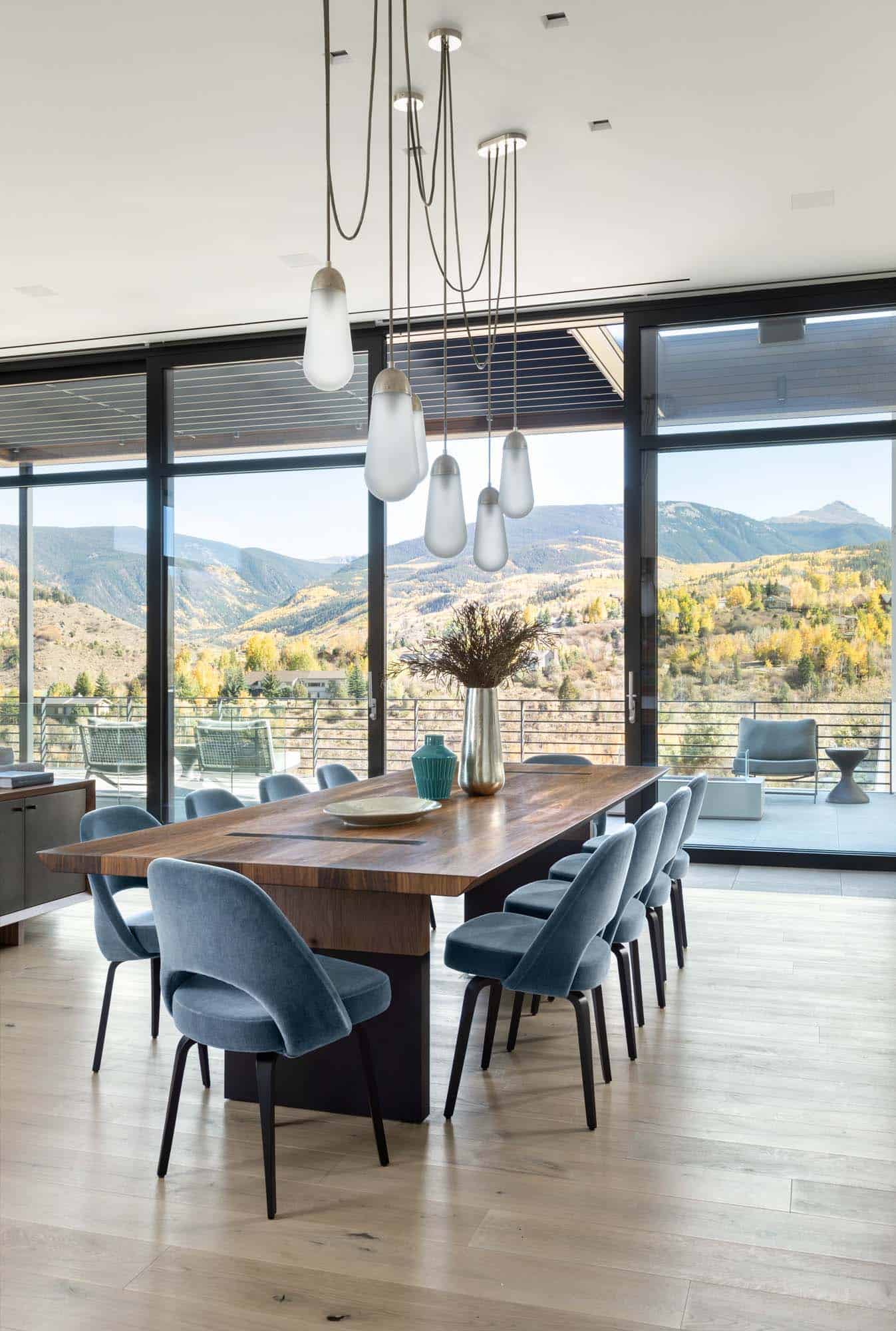 modern dining room with pendant lights and expansive walls of glass with mountain views