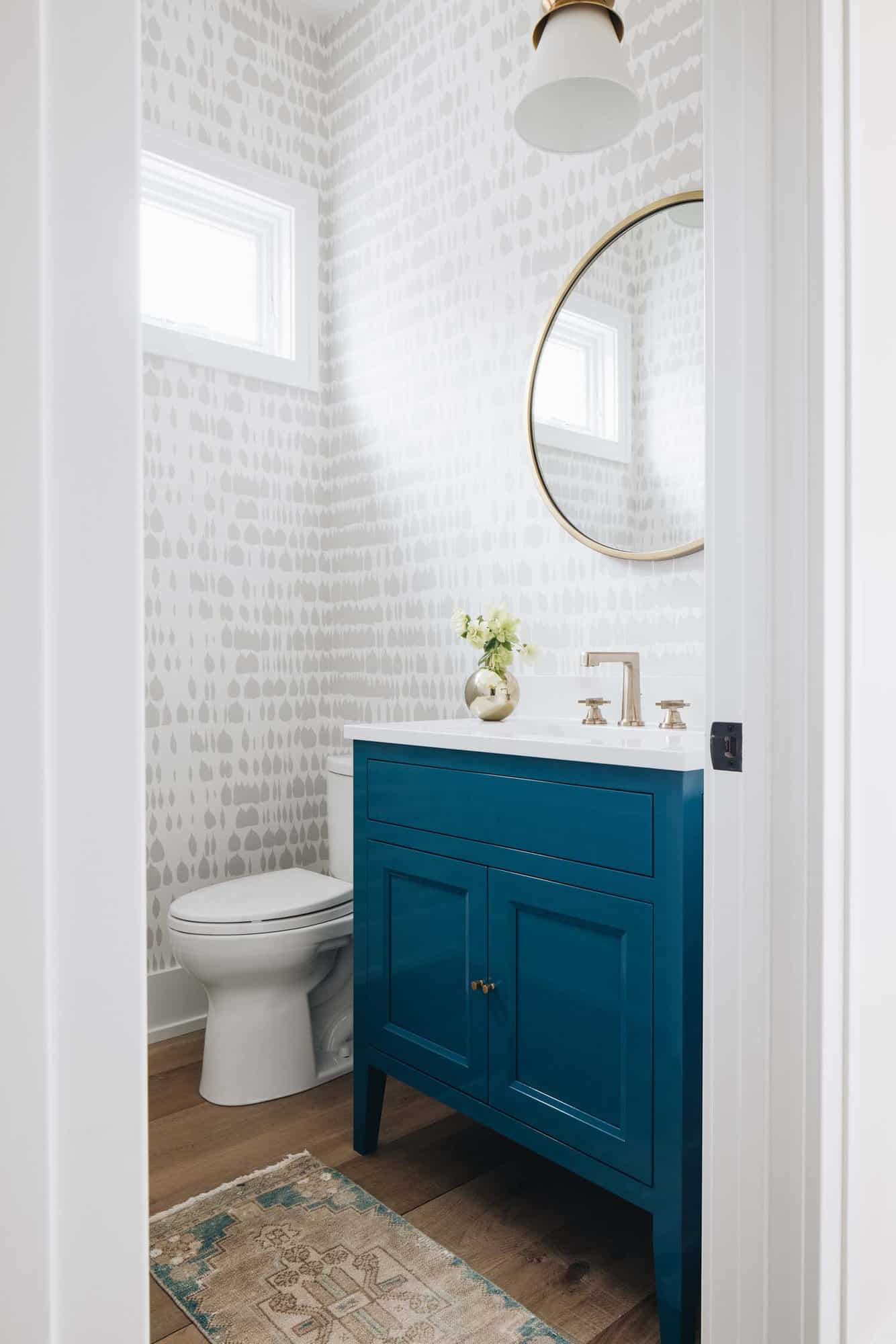 beach style powder bathroom with a blue vanity and wallpaper