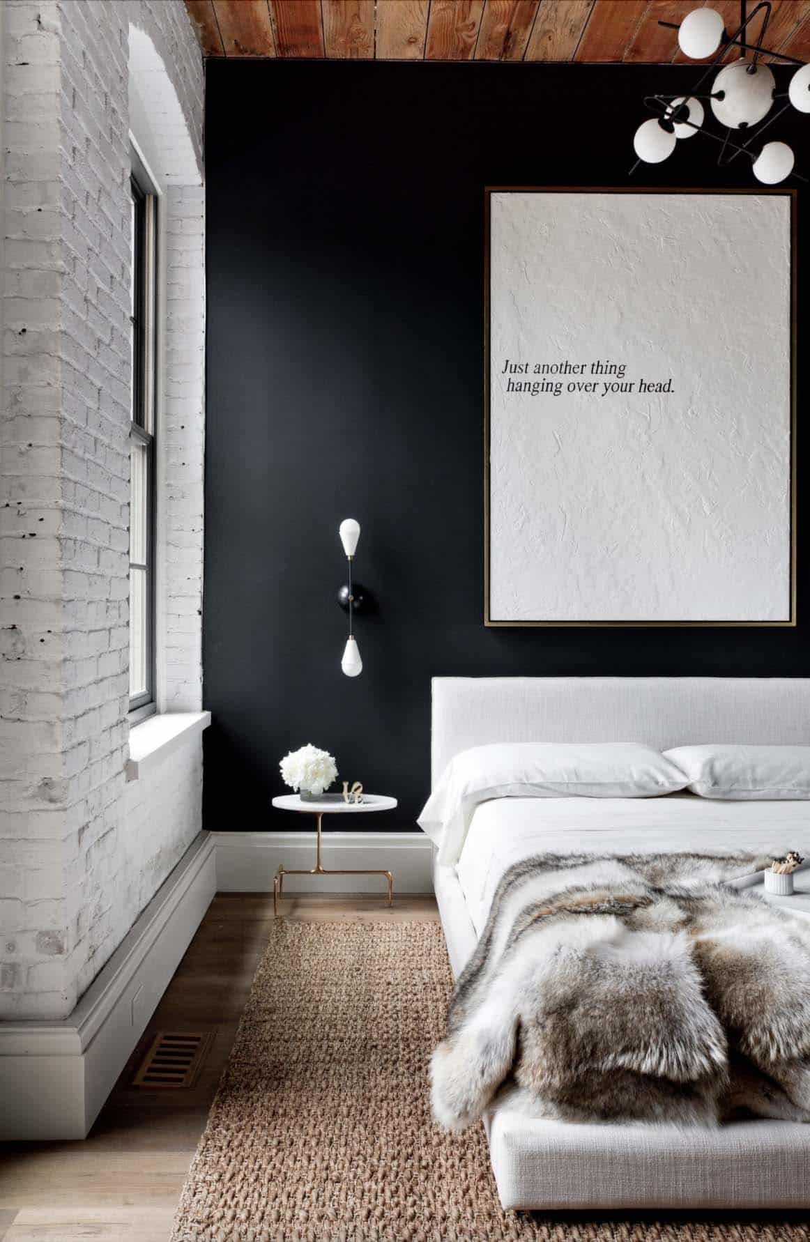 scandinavian style bedroom with a black accent wall and white washed brick walls