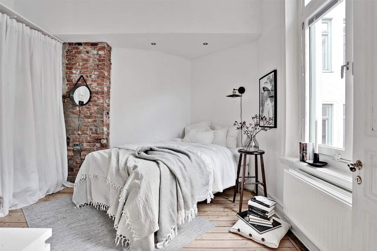 cozy Scandinavian style bedroom with layers of bedding and a brick accent wall