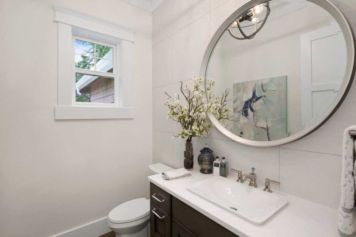 powder room features large tile detail wall and circle mirror.