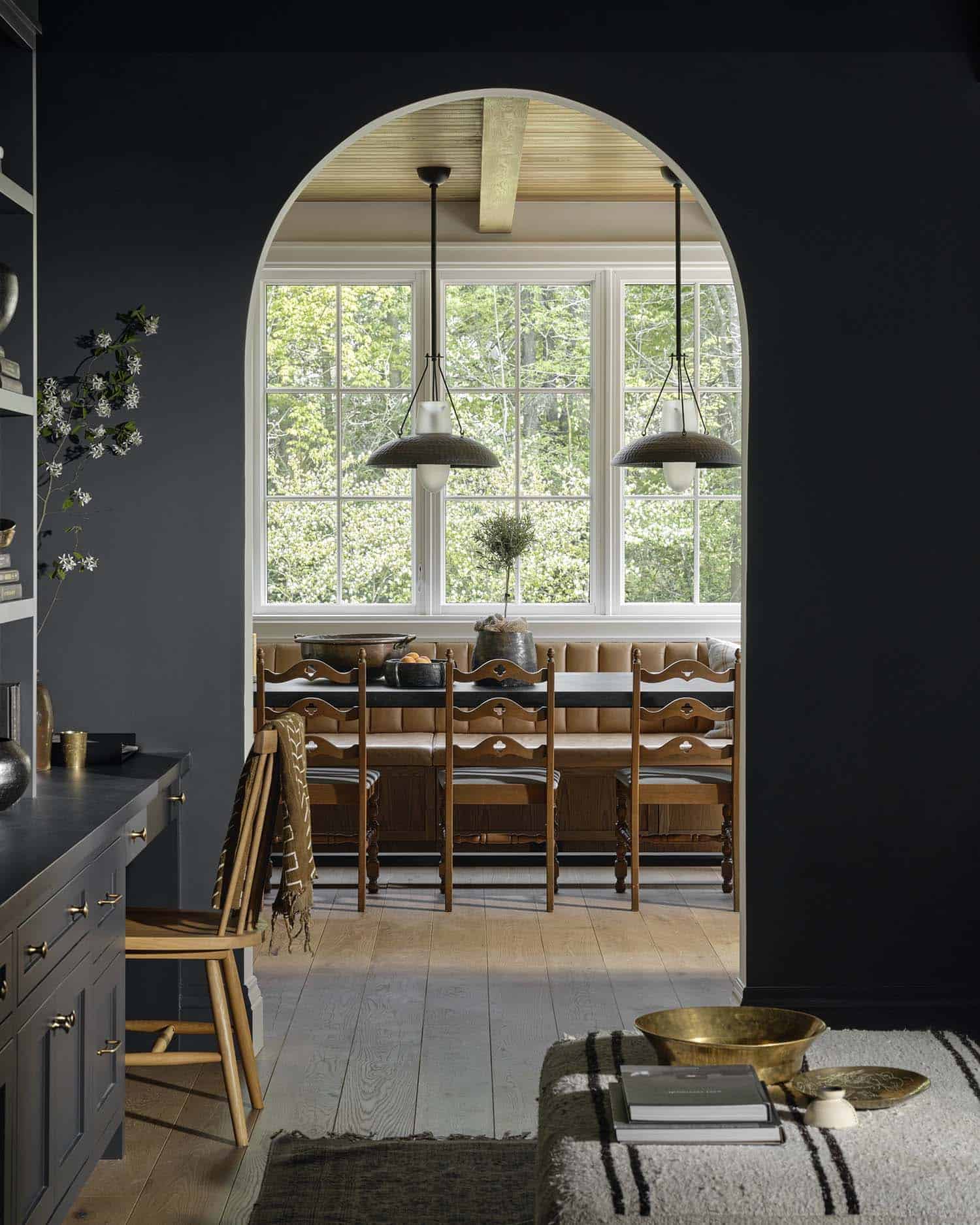 moody home office with an arch doorway and view of the dining room