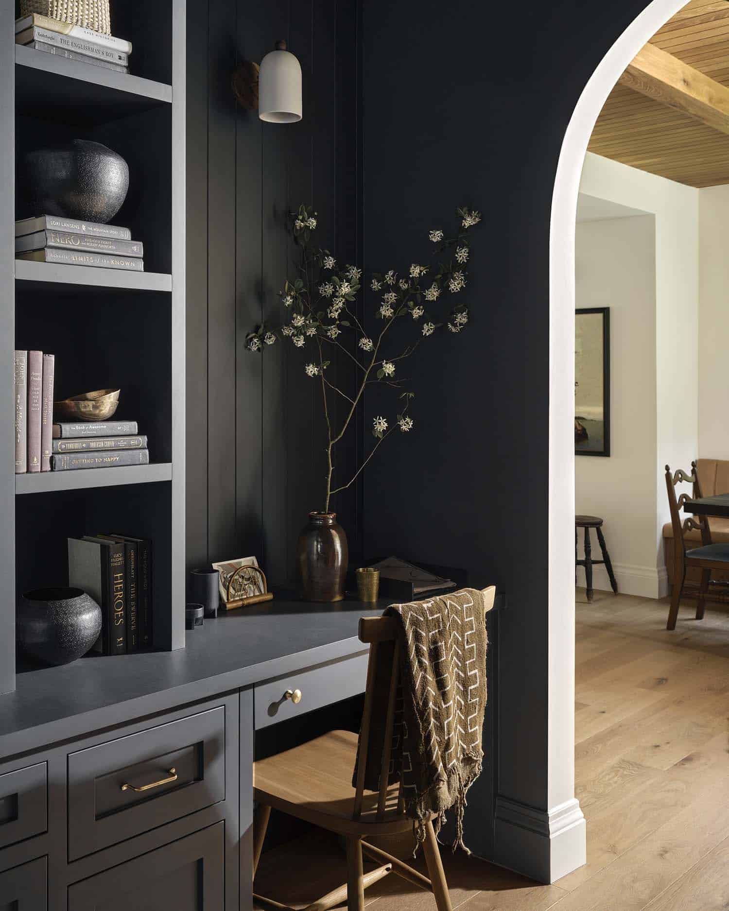 moody home office with an arch doorway and view of the dining room
