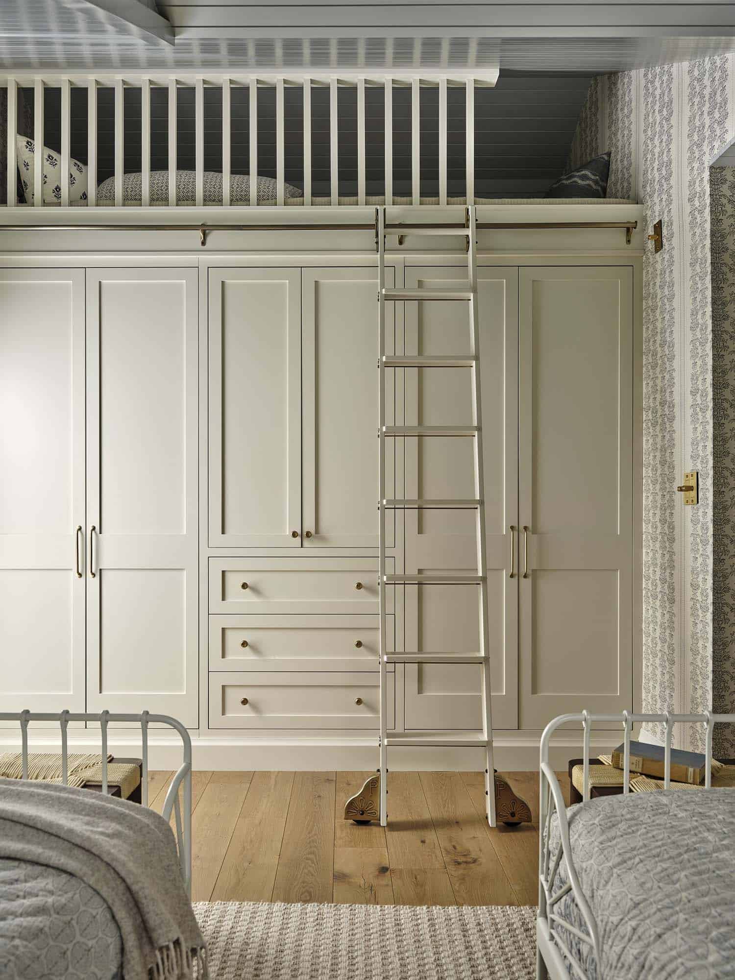contemporary twin bedroom with integrated wall closet and rolling ladder leading up to a loft
