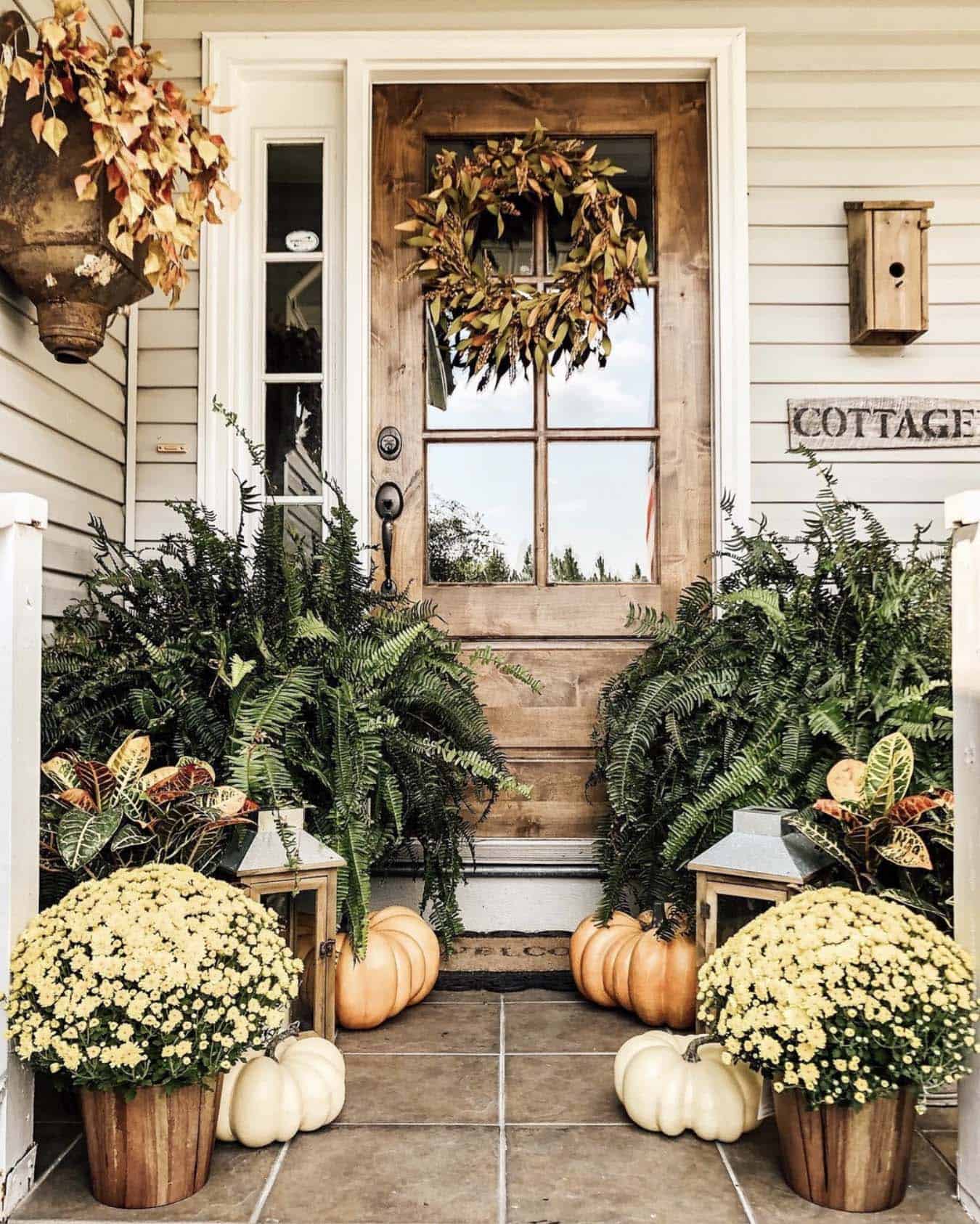 front door with mums, pumpkins and a fall wreath