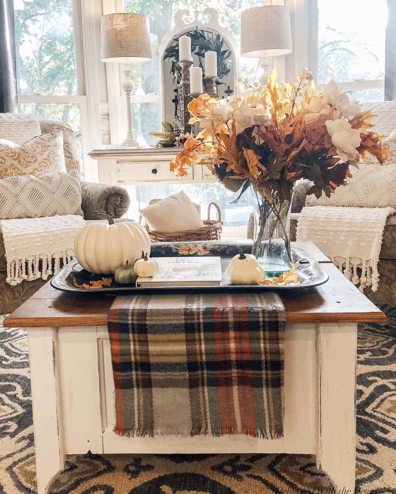 living room with pumpkins, dried flower arrangement and a plaid throw