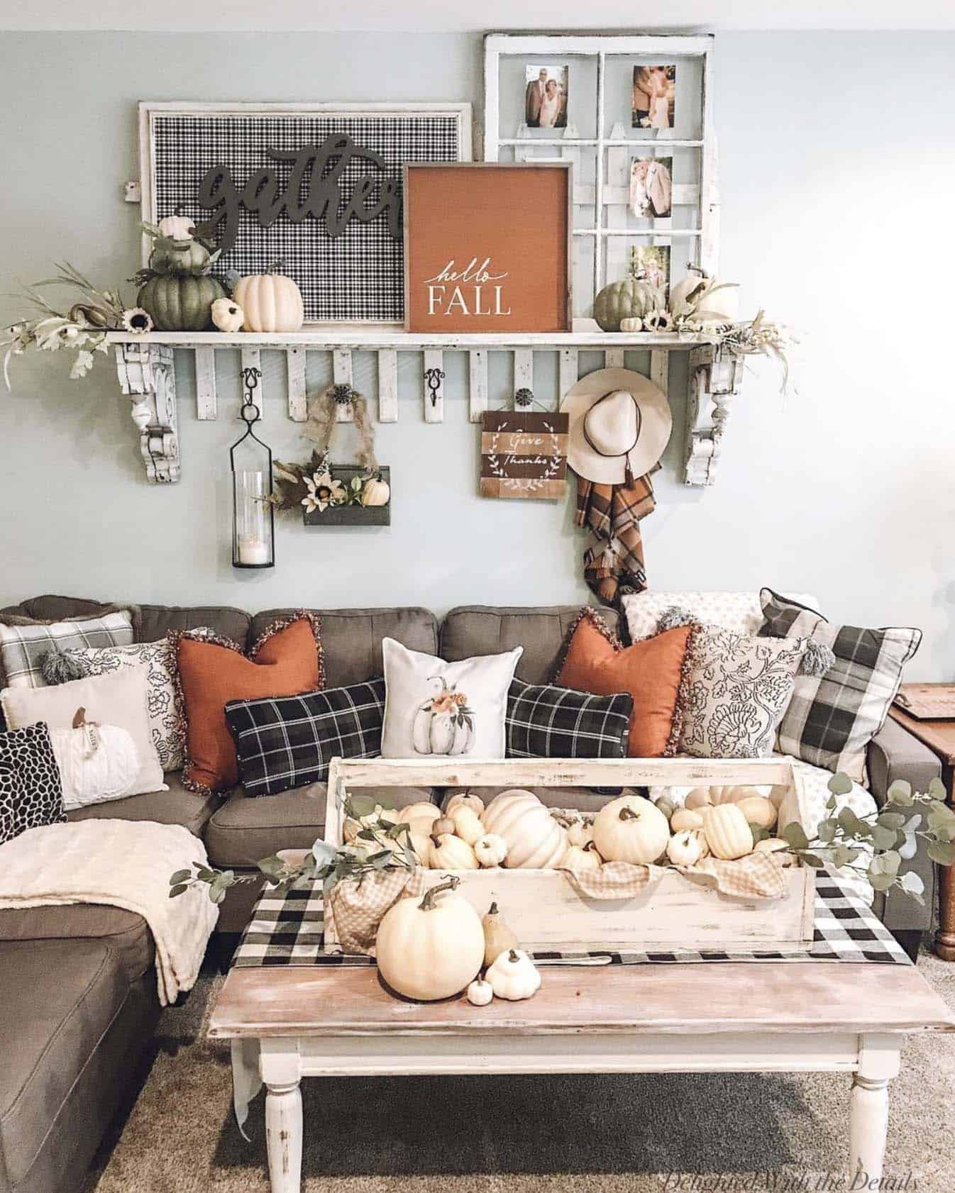 farmhouse-style living room with rustic fall signs, pumpkins, and cozy pillows