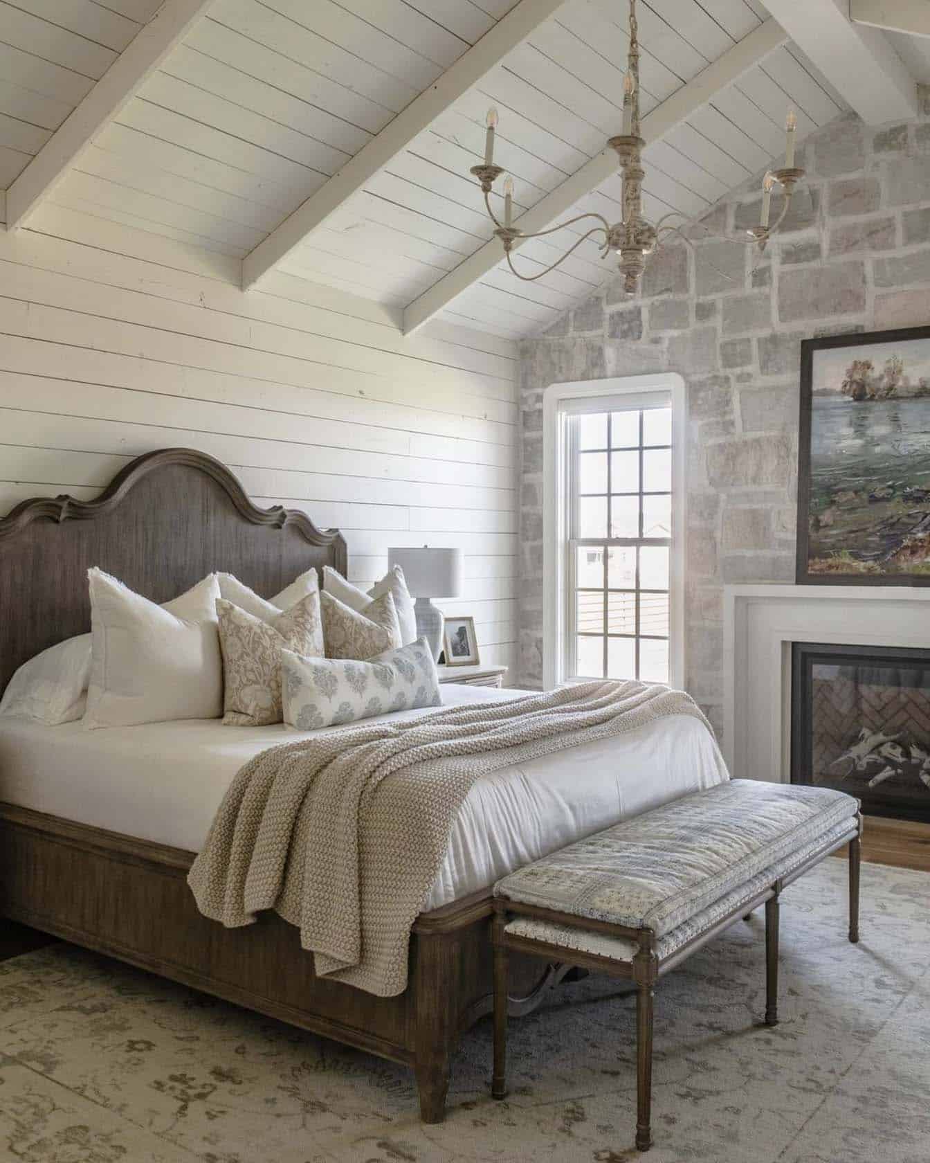 farmhouse style bedroom with a stone wall and fireplace
