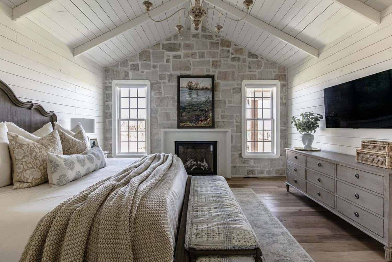 farmhouse style bedroom with a stone wall and fireplace
