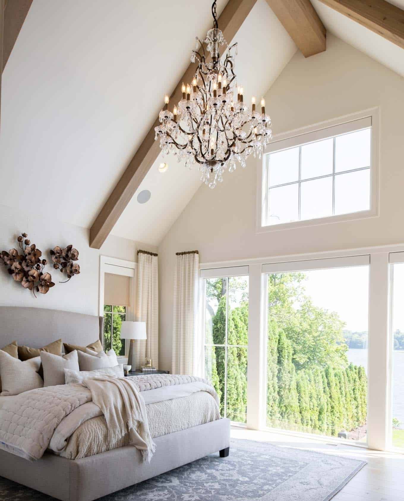 bedroom with large windows, wood beams, a tall ceiling and a chandelier