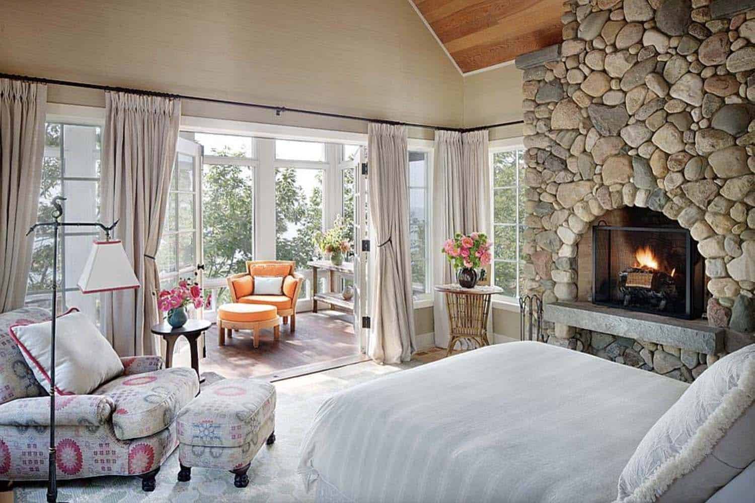 lake house bedroom with a stone clad fireplace and a sunlit sitting room
