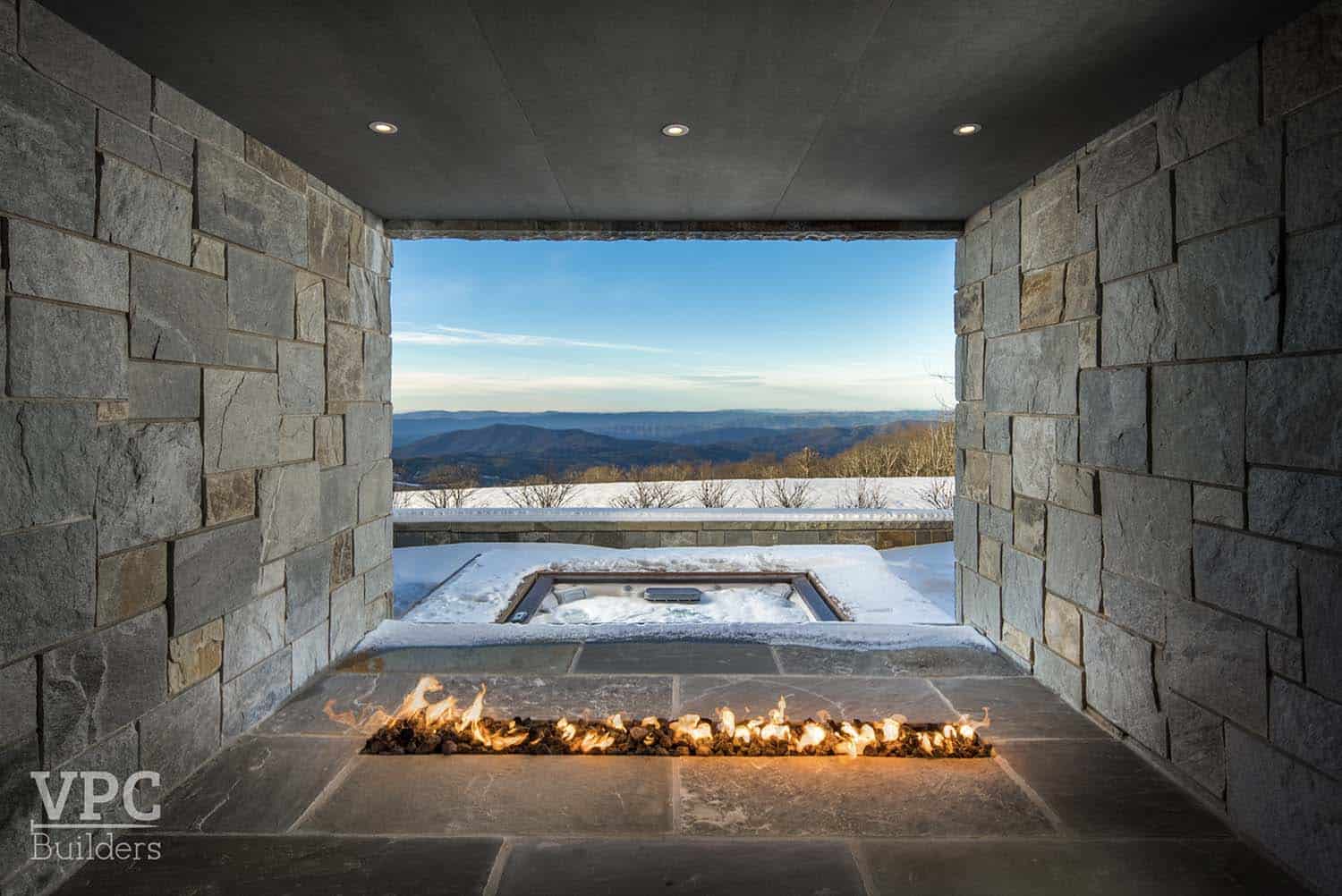 modern mountain lodge outdoor hot tub with a fireplace and snow