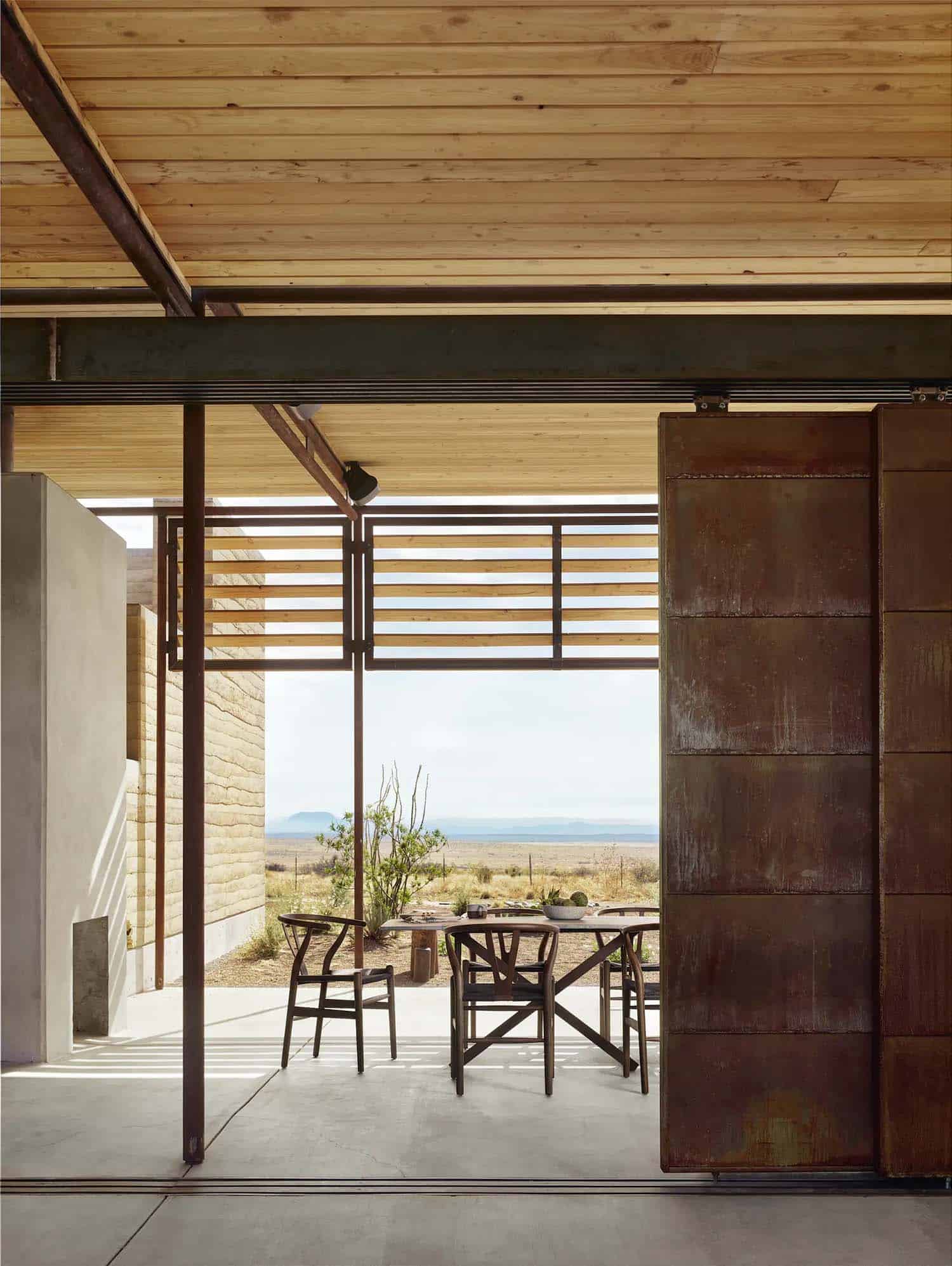 rammed earth ranch house sliding barn door to the outdoor patio