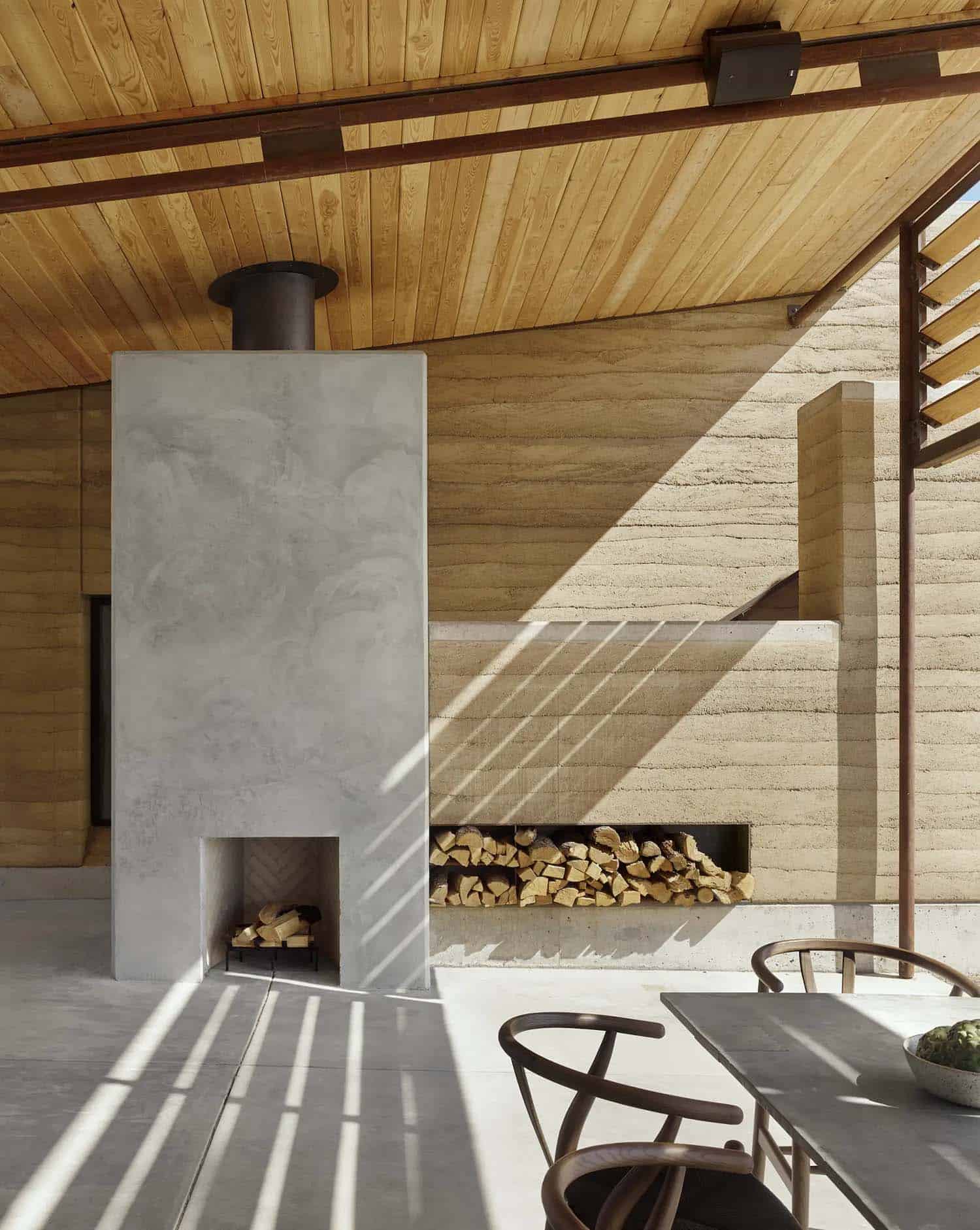 rammed earth ranch house with an outdoor porch and fireplace