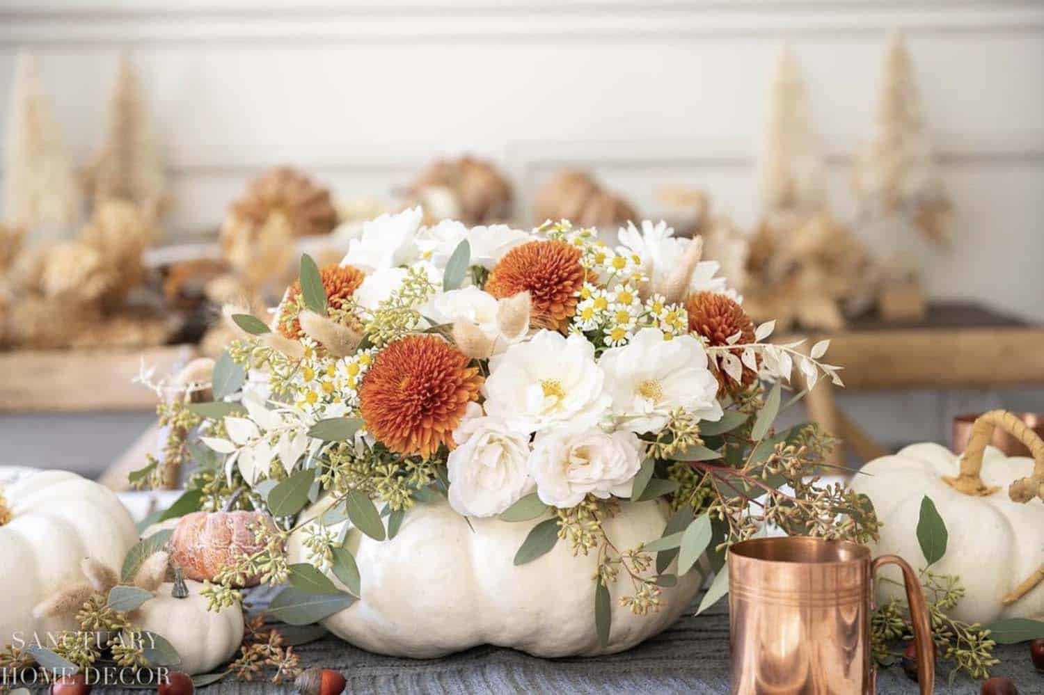 autumn table centerpiece with a large white pumpkin and fall foliage