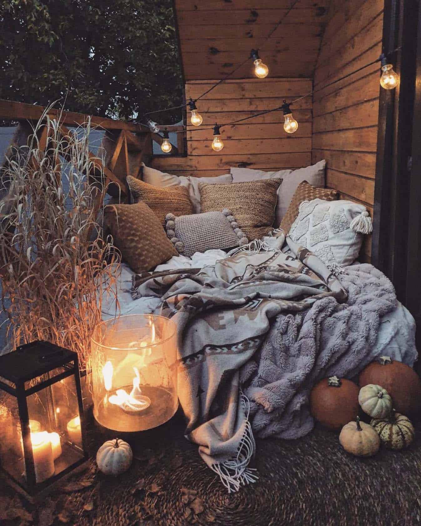 cozy outdoor bed on the balcony with string lights and pumpkins
