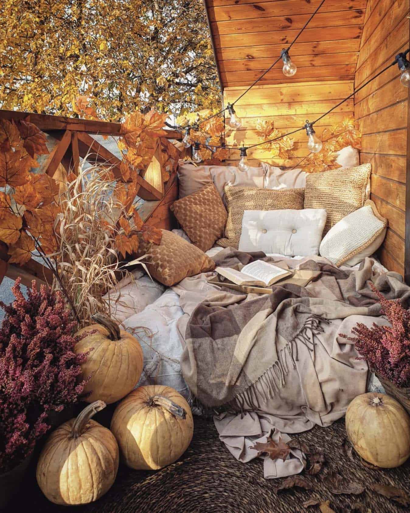 hygge outdoor bedroom with string lights, fall leaves, and pumpkins