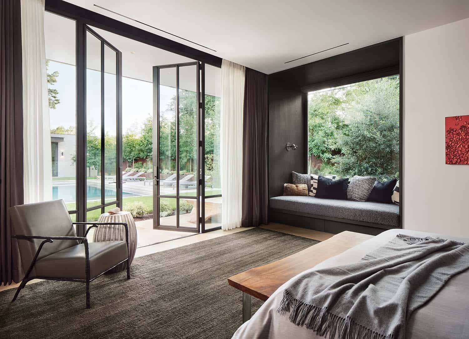 modern bedroom with a window seating and folding glass doors leading out to the backyard patio