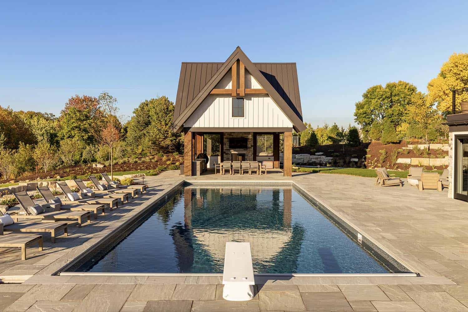 rustic pool with a large deck and pool house
