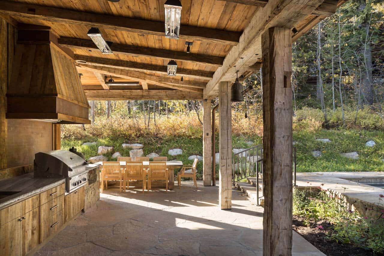 rustic mountain style covered patio with an outdoor kitchen and dining area