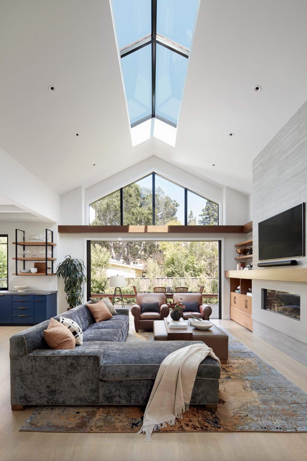 transitional living room with a wall of glass and a skylight