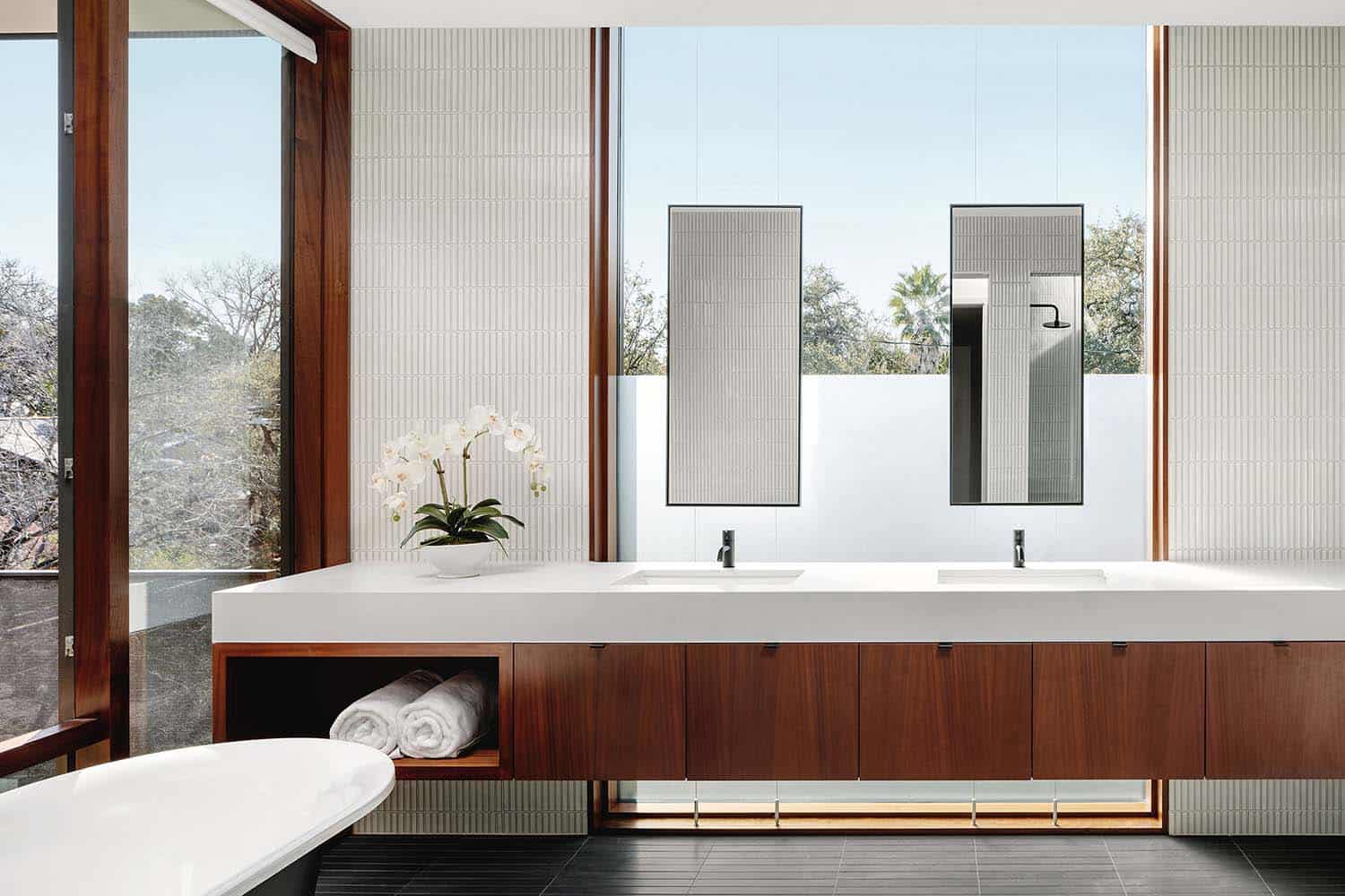 modern bathroom with a window behind suspended mirrors above the vanity