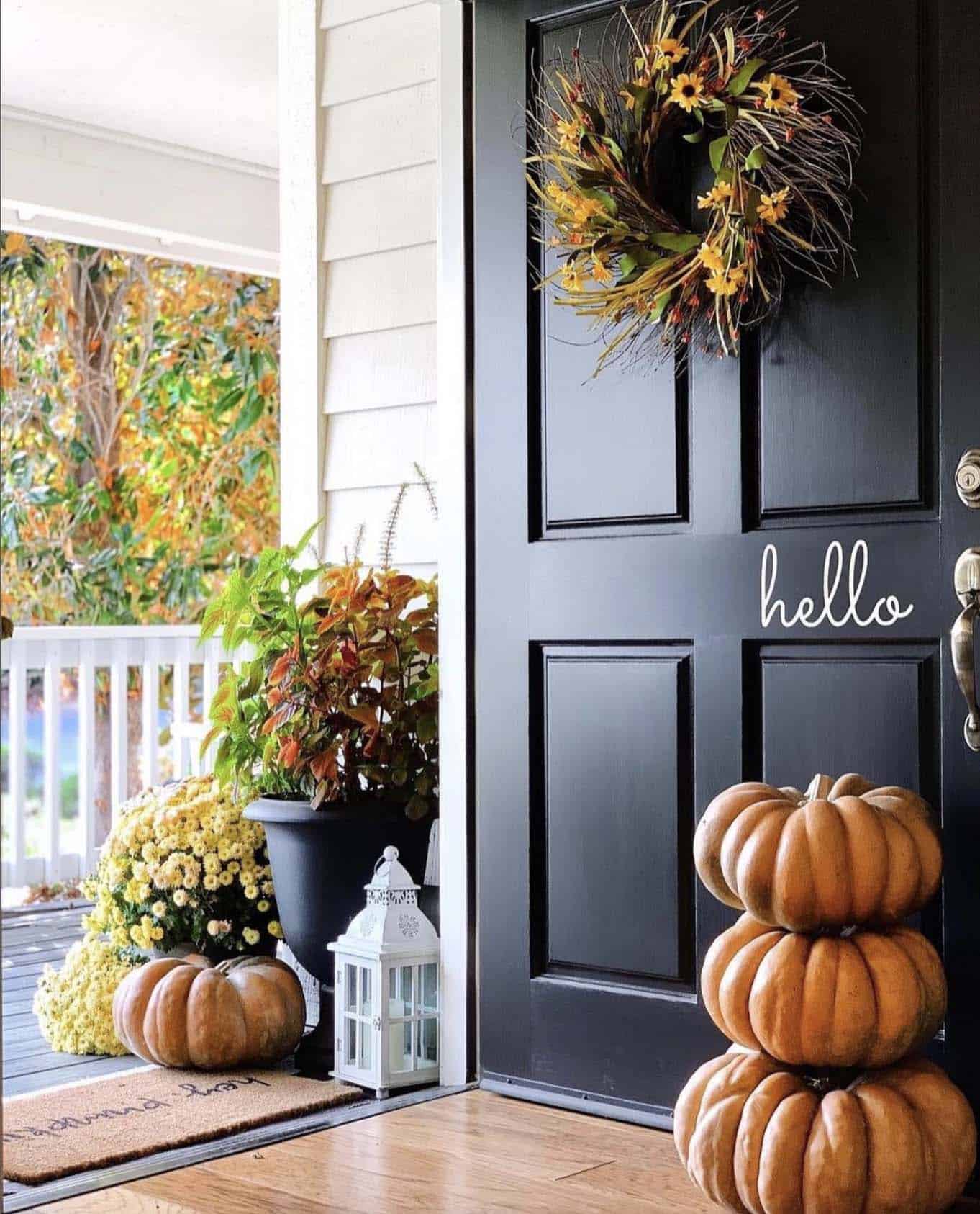 fall decorated home entry with a wreath and stacked pumpkins