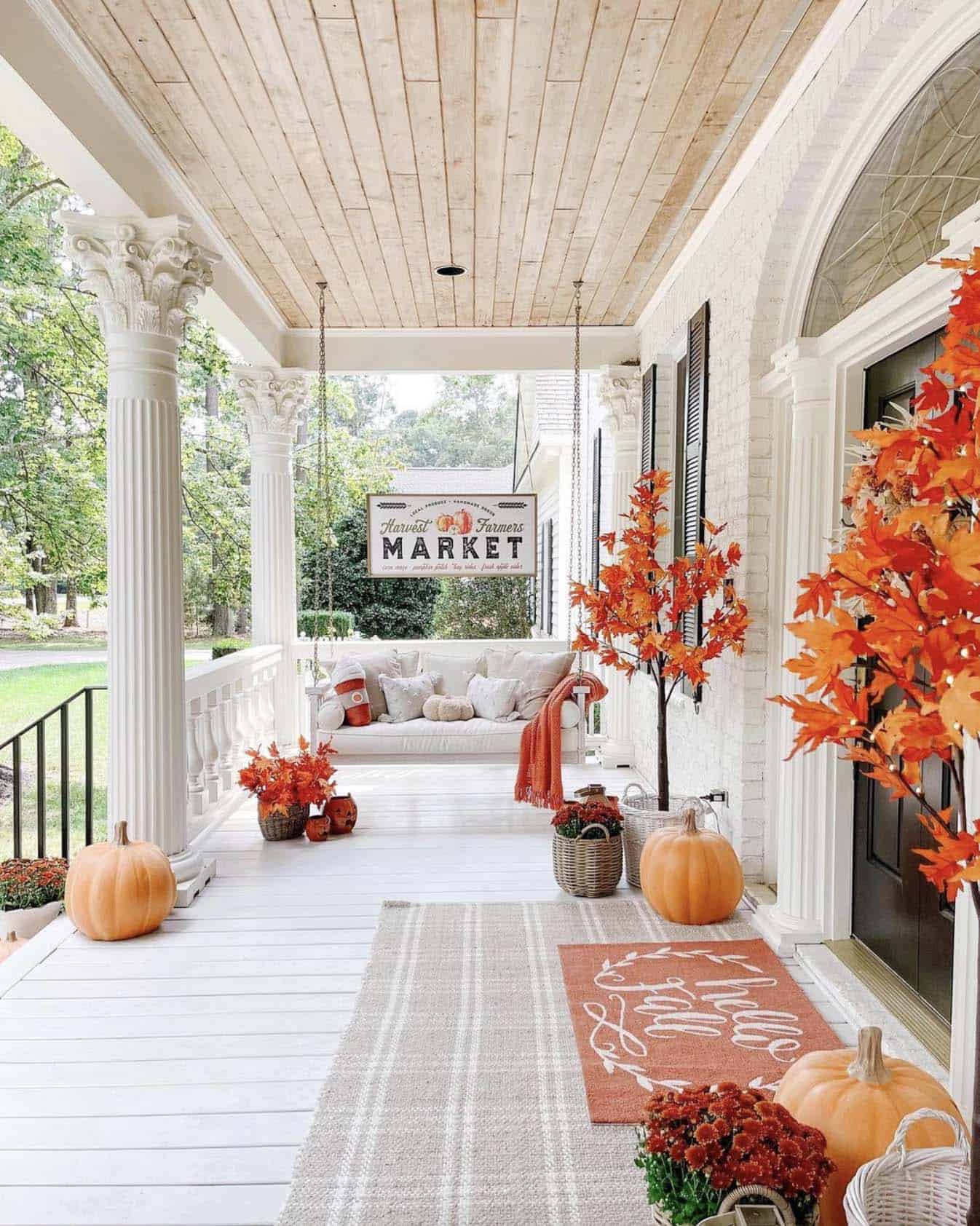 fall front porch with a hanging swing and maple trees