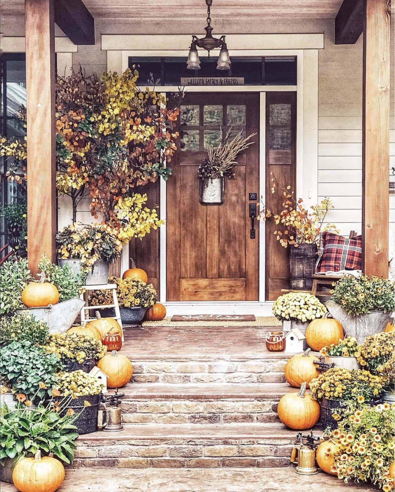 rustic fall porch with pumpkins and baskets full of mums