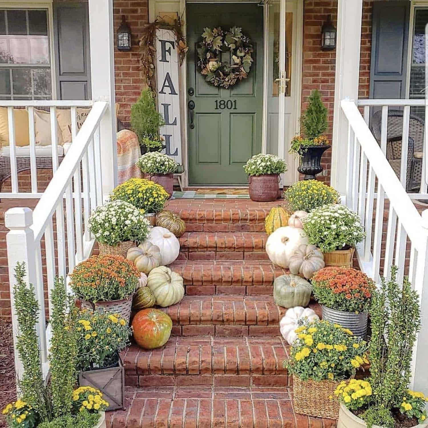 fall porch with a green front door and steps decorated with pumpkins, mums, and a fall sign