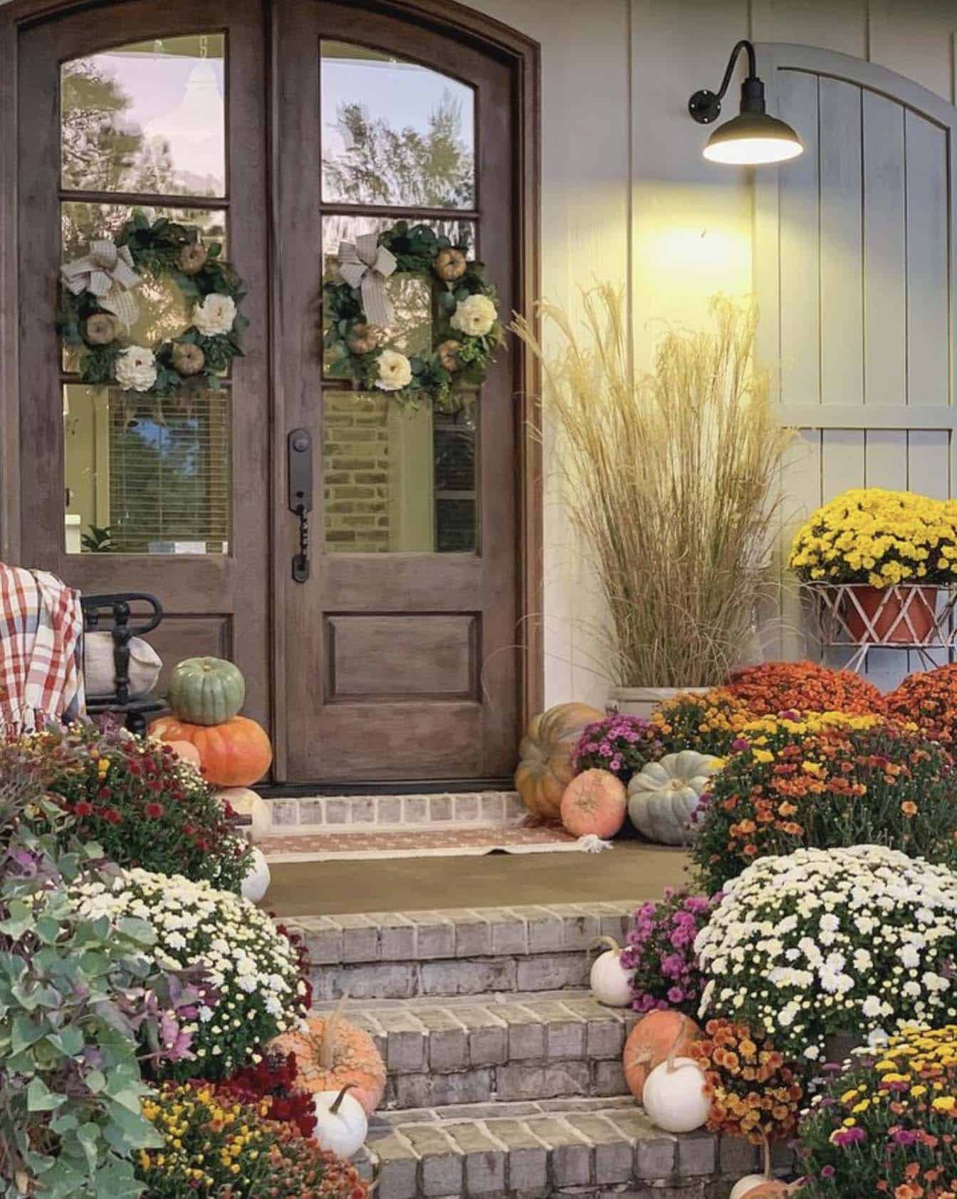 fall front porch with mums and pumpkins and door wreaths