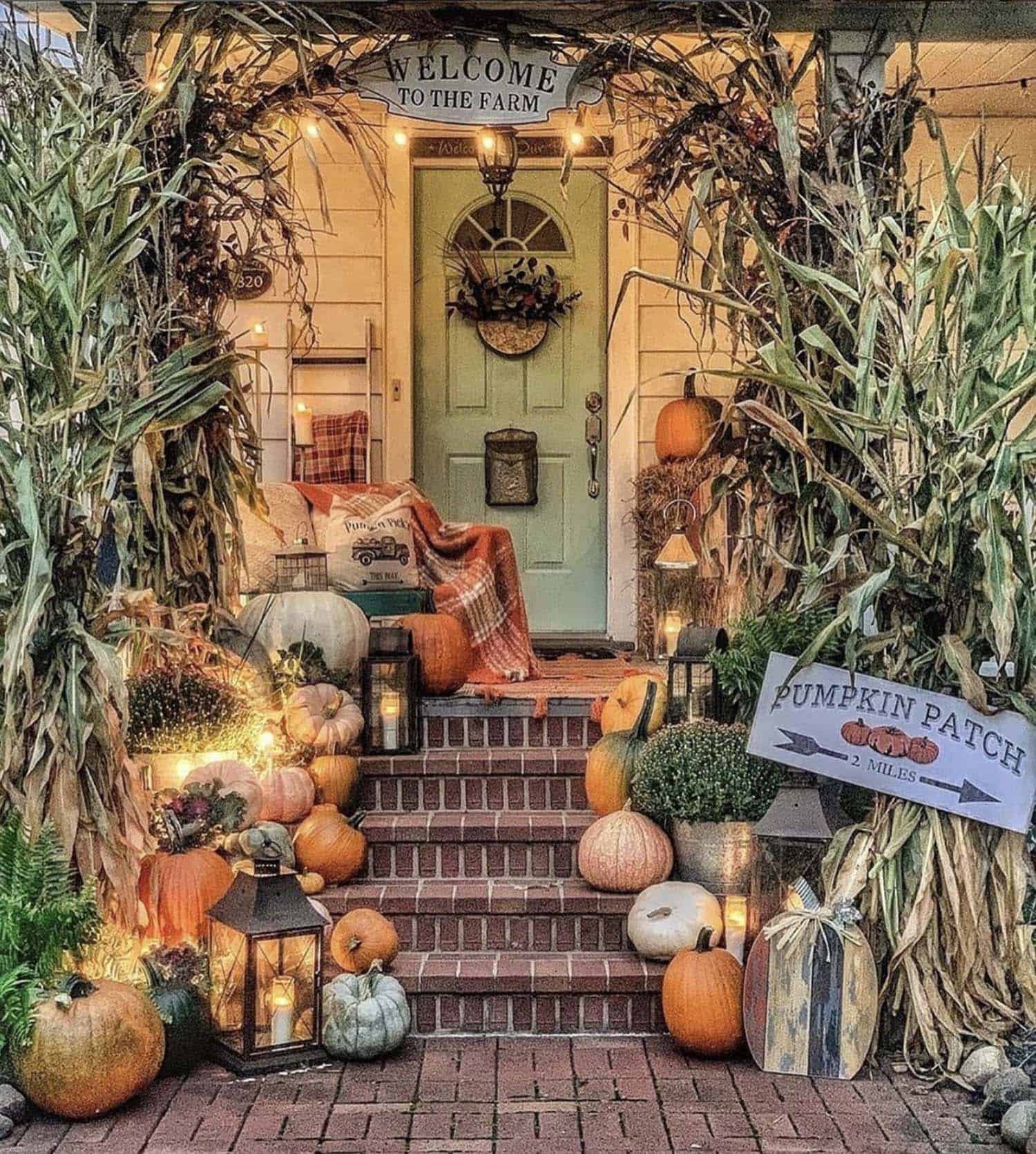 farmhouse front porch decorated with pumpkins, cornstalks, lanterns and fall signs