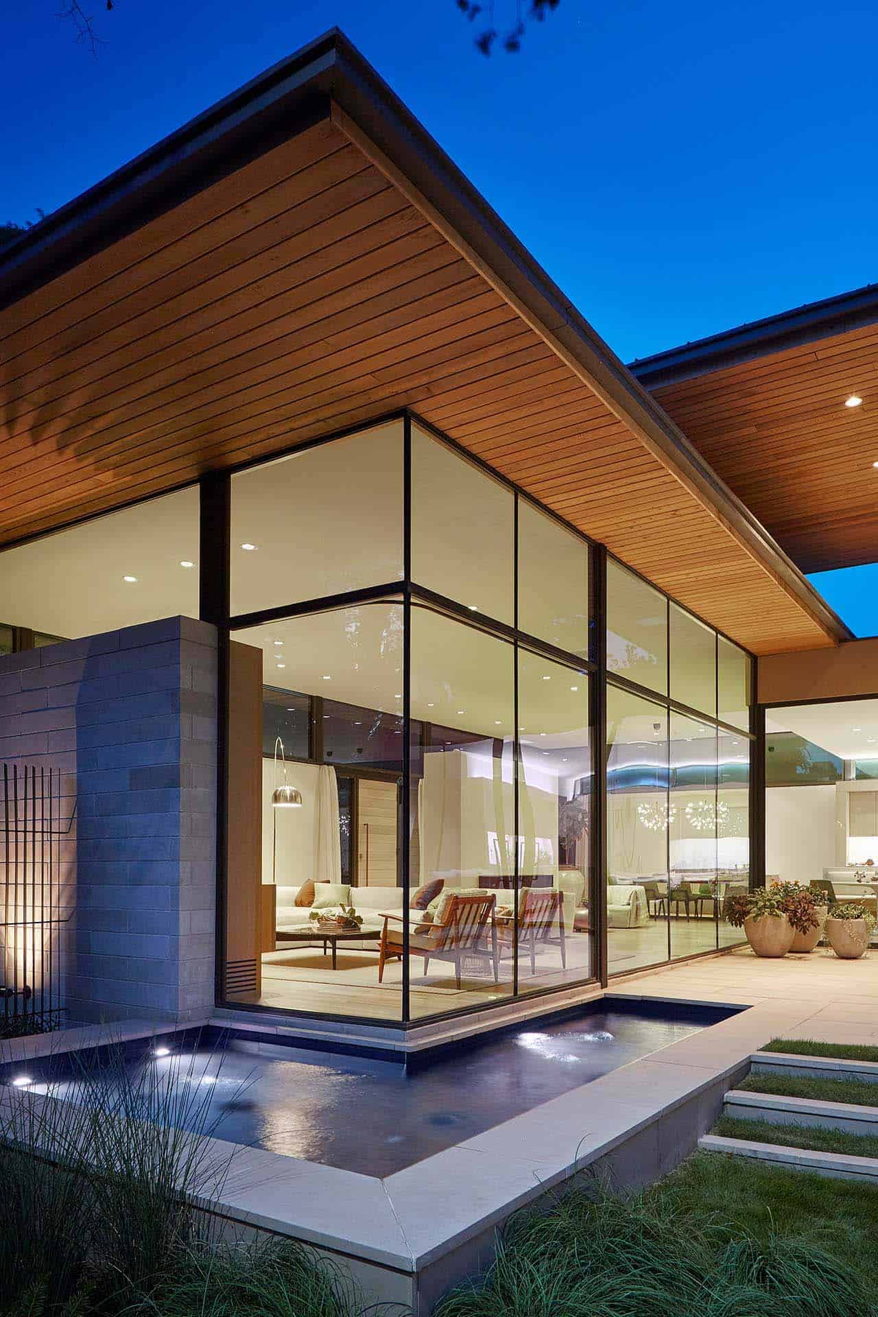 modern courtyard house exterior backyard patio with a swimming pool at dusk