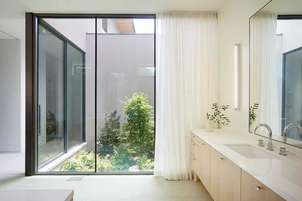 modern bathroom with a large window framing an outdoor courtyard