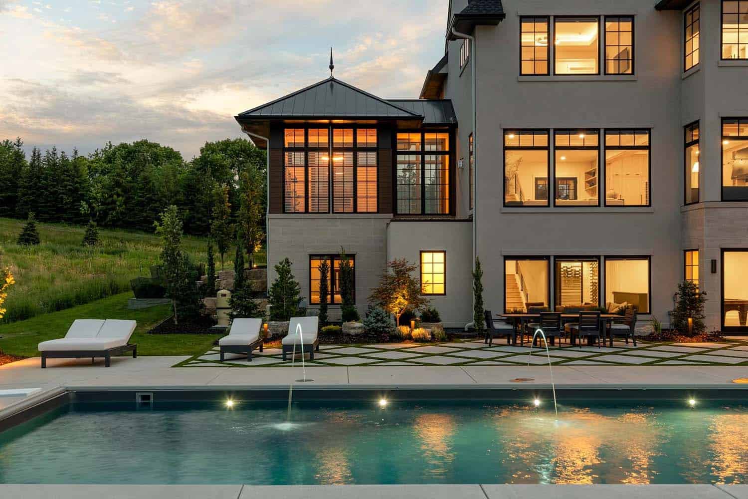 modern home exterior with a swimming pool at dusk