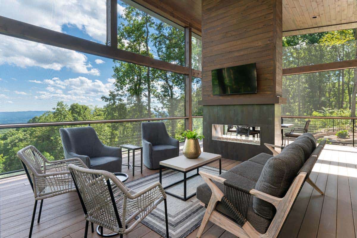 moody modern screened porch with a fireplace and outdoor television