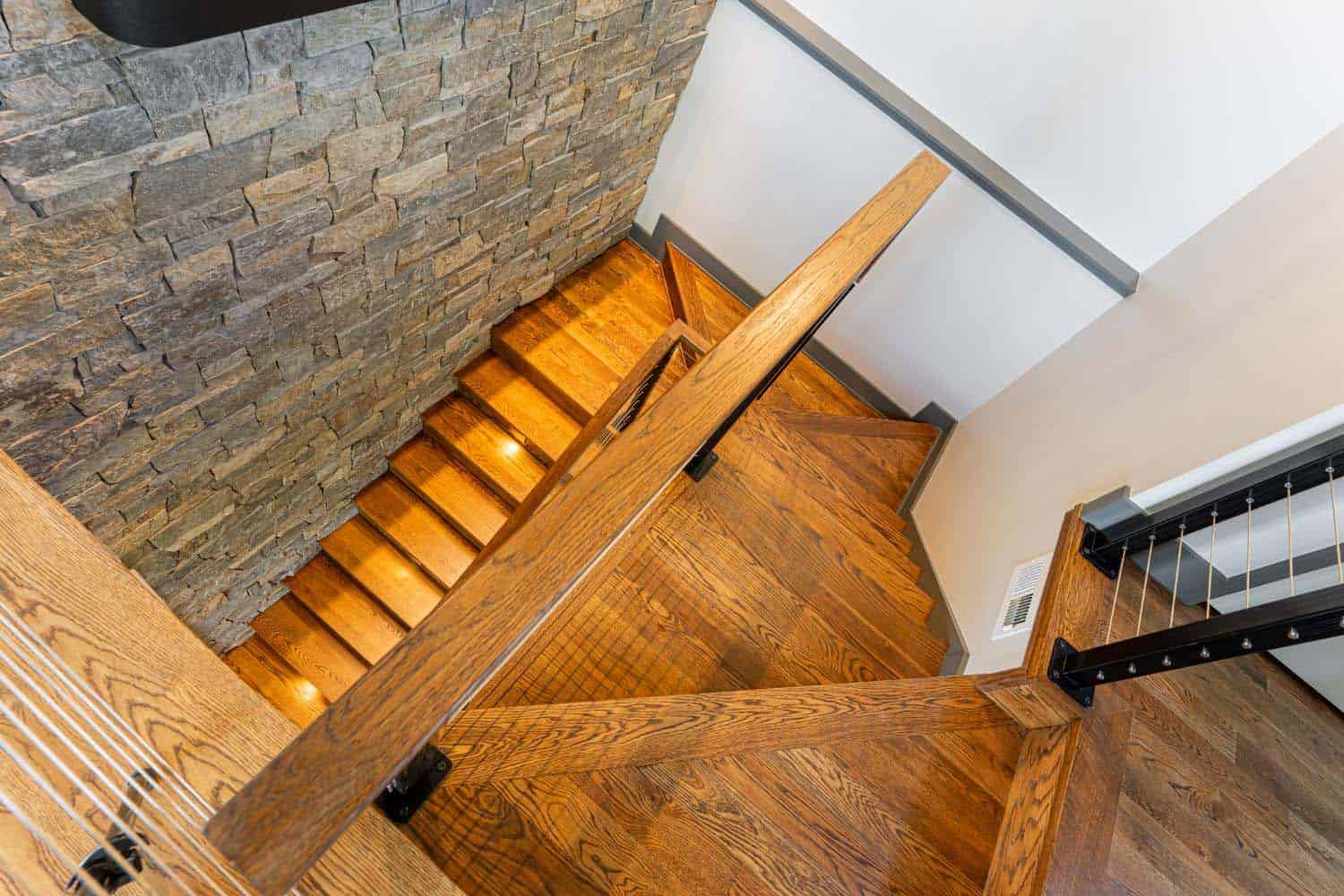 modern staircase with a stone clad wall